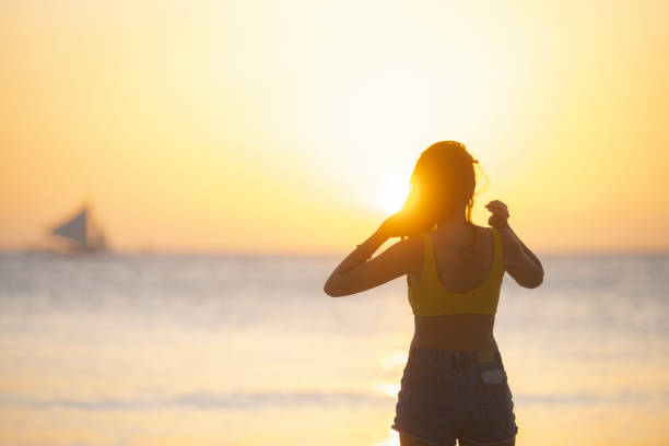 (orientation sélective) vue imprenable de la silhouette d’une fille marchant sur une plage pendant un coucher de soleil beau et romantique. white beach, boracay island, philippines. - people traveling elegance philippines palawan photos et images de collection