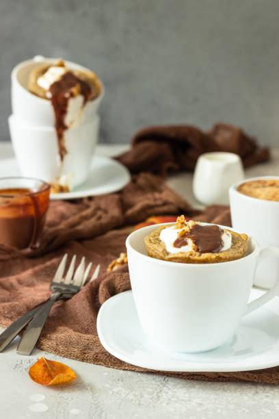 istock Carrot or pumpkin mug cupcake with whipped cream, caramel sauce and walnuts in a white ceramic mug. Cozy autumn or winter breakfast. Healthy dessert. 1208960812