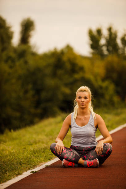 istock Athletic female sitting on a running track and stretching before a run 1208962247