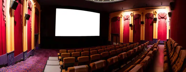Photo of Cinema theater showing empty white movie screen.
