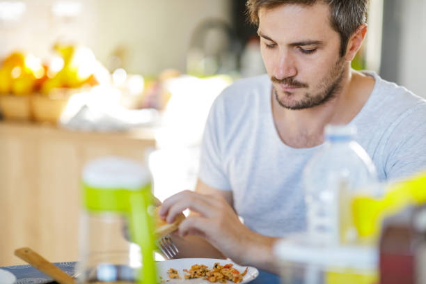 istock Young man having omelet with vegetables for breakfast 1208970347