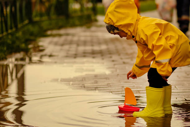 istock little boy plays with a plastic boat in a puddle on a rainy autumn day. 1208970475
