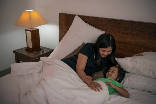 istock Indonesian child smiles while her mother snuggles her bed 1208971257