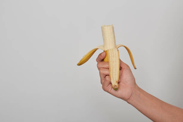 istock Female hand holding a banana on white background 1208974226