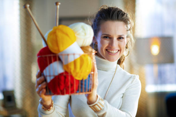 istock smiling trendy female showing basket with yarn and needles 1208978080