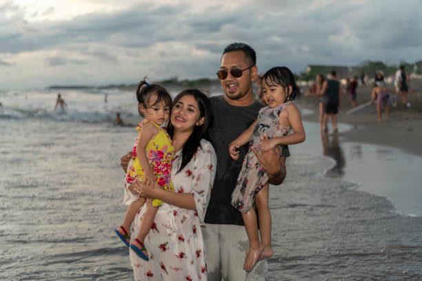 istock Indonesian parents hold their two daughters at a beach on sunset 1208978233
