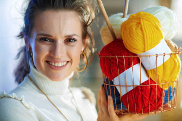 istock smiling woman showing basket with yarn and needles 1208978381