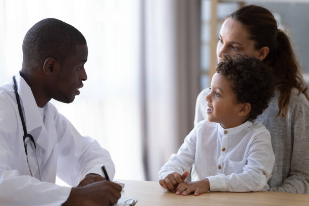 junge afrikanische amerikanische männliche kinderarzt hören kleine patientenbeschwerden. - family african ethnicity black african descent stock-fotos und bilder