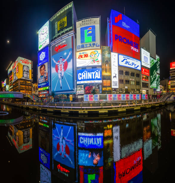 The iconic neon billboards of Dotonbori reflecting in the tranquil waters of the eponymous canal as the moon rises over Osaka, Japan’s vibrant second city.