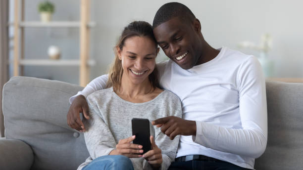 istock Happy young mixed race family couple using mobile phone. 1208979588