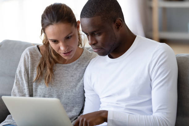 Focused husband showing his interested wife new online banking application.