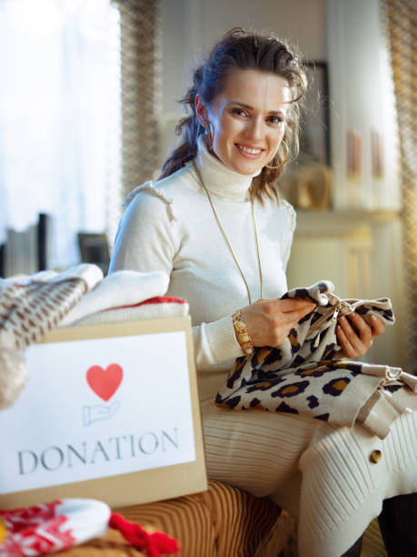 istock happy elegant woman packing donation box with clothes 1208979628