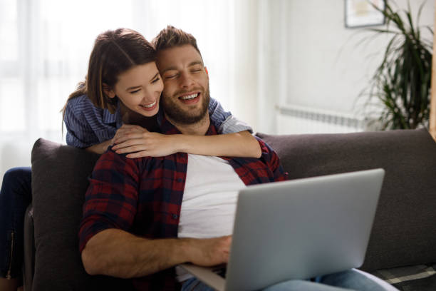 istock Young couple using a laptop while relaxing on the sofa at home 1208979652