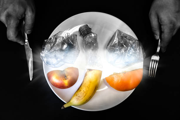 istock Plastic bottle and fruit on the plate. People eating polluted food. Environmental issue. Ecological disaster. Recycling problem. Hands with knife and fork. 1208982999