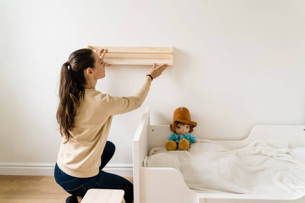 Young woman renovation child room in new house. Wooden bookshelf. Neutral nursery stock photo