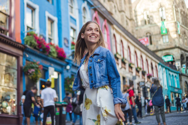 Modern female tourist spending excited day visiting Victoria street in Edinburgh Beautiful young woman in dress, exploring architectural beauty of Victoria street ina Edinburgh on a sunny summer day denim jacket stock pictures, royalty-free photos & images