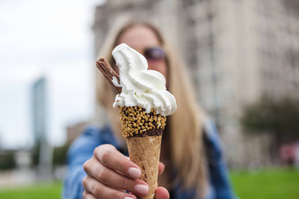 istock Modern woman holding vanila ice cream in cone decorated with chocolate 1208988398