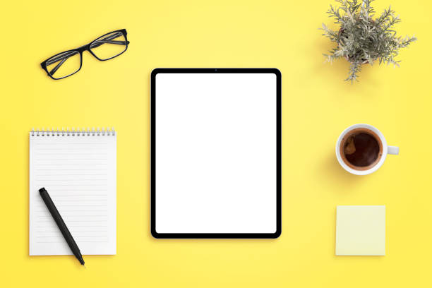 istock Tablet mockup on yellow office desk. Isolated screen for app or web site design promotion. Pad, pen, cup of coffee, glasses and plant beside 1208989424