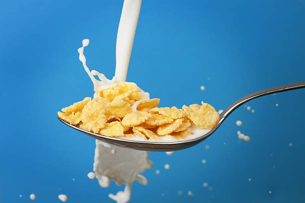istock milk splashing into spoon with cornflakes over blue background 120899117