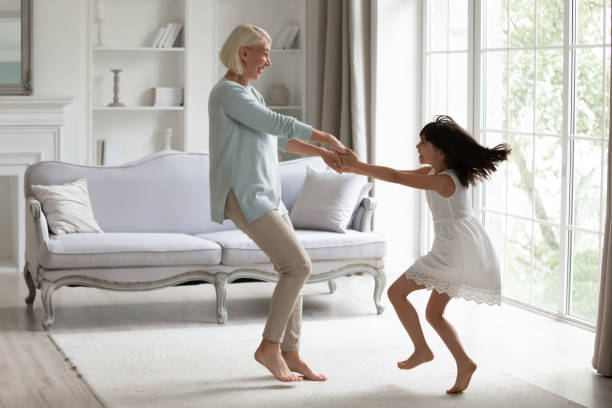 energetische großmutter haben spaß beim tanzen mit der kleinen enkelin - grandmother and grandaughter stock-fotos und bilder