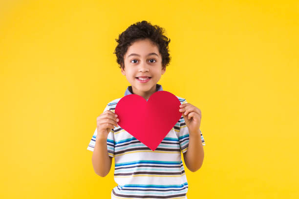 menino de etnia negra isolado em fundo amarelo - heart shape child human hand childhood - fotografias e filmes do acervo