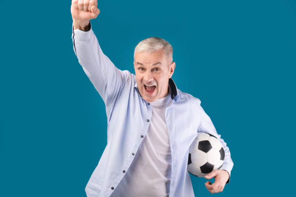 istock Man posing with soccer ball on blue studio wall 1208995349