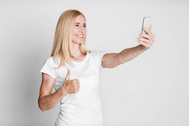 istock Aged woman taking photo of herself at studio 1208995357