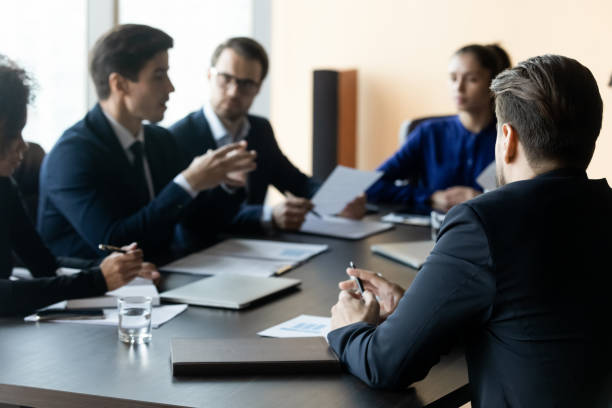 Close up businessman back sit at table in boardroom. Close up businessman back sit at table in boardroom at company meeting. Confident employee listens business mentor telling about business strategy with colleagues at briefing. politician stock pictures, royalty-free photos & images