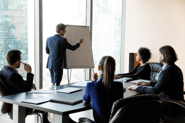 istock Confident businessman writing on flip charts presentation new project. 1208998499