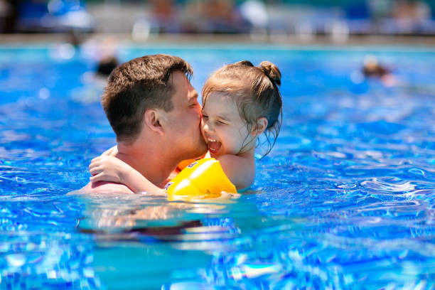 istock dad and daughter play and cuddle in the pool. 1209000658