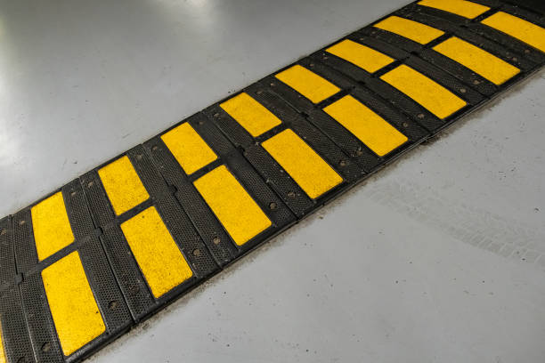 istock Striped black and yellow speed bump on a road. 1209001744