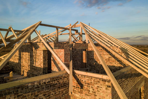 istock Private residential house with wooden roof frame structure under construction. Unfinished brick building under development. 1209001881