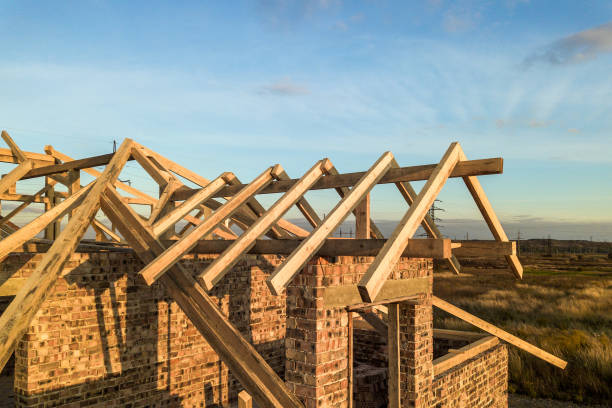 istock Private residential house with wooden roof frame structure under construction. Unfinished brick building under development. 1209001891