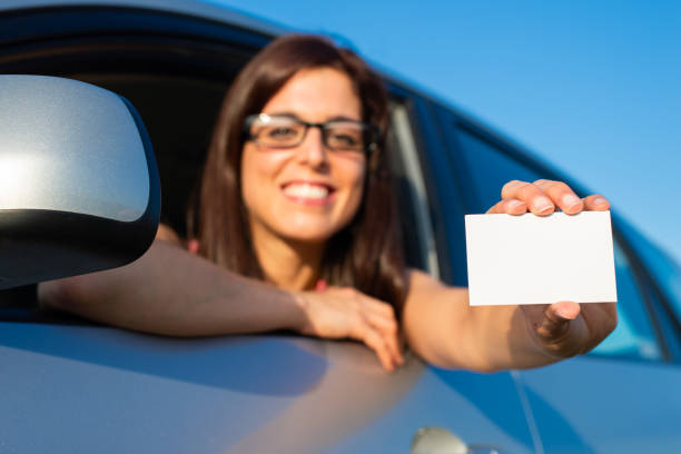 istock Woman in car showing driving license 1209001929