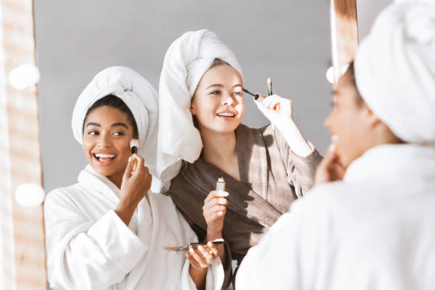 istock Girlfriends in bathrobes getting ready for party, putting make up 1209003652