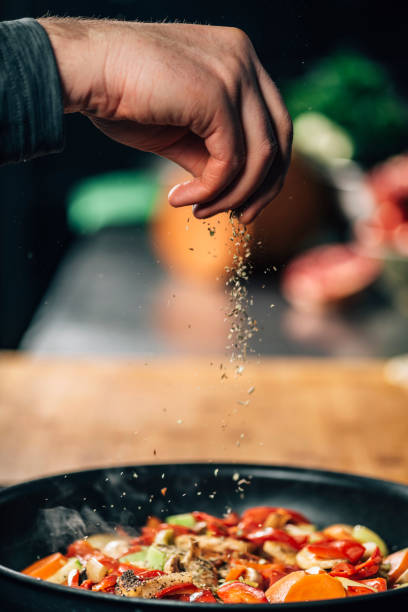 istock Seasoning - Chef Sprinkling Oregano over Vegetables 1209004185
