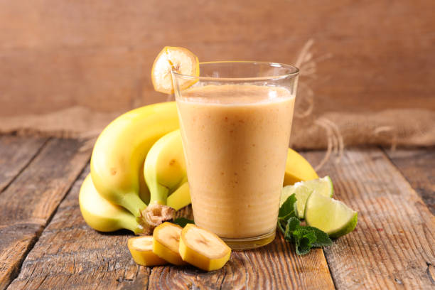 istock banana smoothie, fruit juice on wood background 1209005186