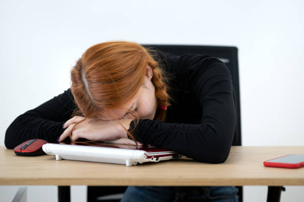 istock Tired office worker woman having a nap behind working desk. 1209006753