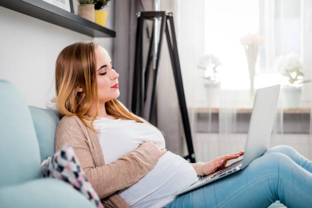 istock Young pregnant woman using laptop sitting on sofa at home 1209006780