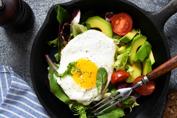 Salad with tomatoes and avocado, fried in a pan for breakfast.