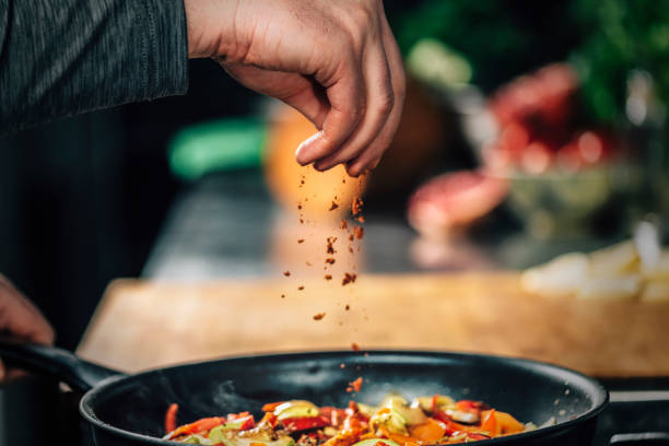 Sprinkling Ground Red Chili Pepper Paprika over Sliced Vegetables Sprinkling ground red chili pepper paprika over sliced vegetables, motion blur seasoning stock pictures, royalty-free photos & images