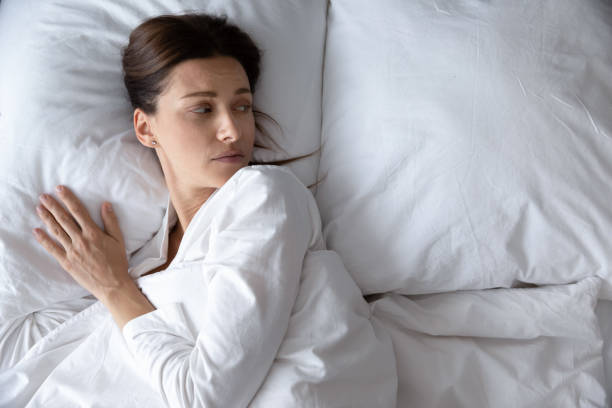 istock Top view unhappy young woman lying in bed alone 1209008692