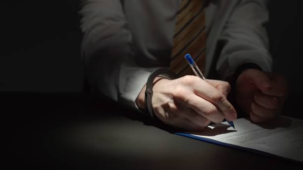 istock Businessman Wearing Formal Clothing Signs A Document With Hands Handcuffed 1209010008