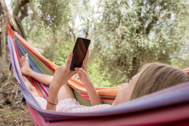 istock girl with smartphone lying in hammock 1209010380