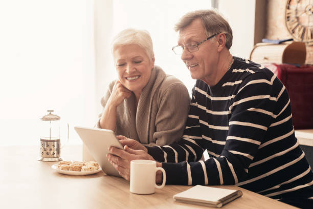istock Cheerful elderly couple using digital tablet in kitchen together, reading news 1209010649