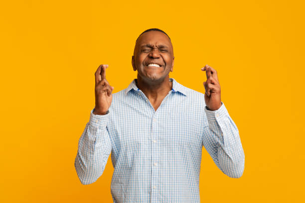 reife afrikanische amerikanische mann kreuzt seine finger - praying joy indoors lifestyles stock-fotos und bilder