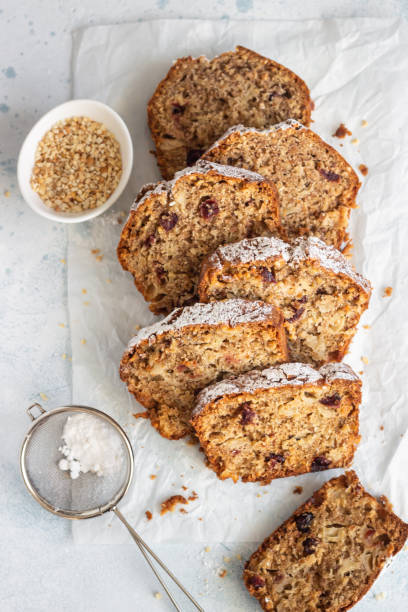 maçã picante, nozes e bolo de pão de cranberry seco decorado com açúcar em pó em um papel. - bolo ingles - fotografias e filmes do acervo