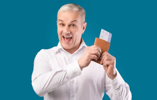 Photo of Excited man holding tickets and passport at studio