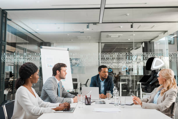 istock young multicultural businesspeople sitting at desk in conference hall together with humanoid robot 1209011987