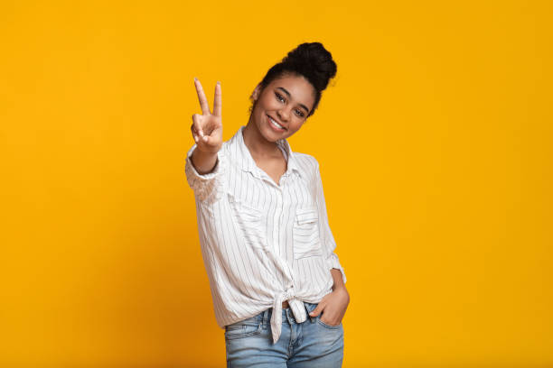 istock Smiling Afro Girl Showing Peace Gesture And Posing At Camera 1209014820